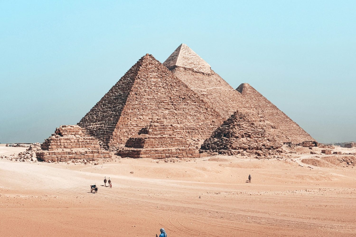Excursión a El Cairo desde El Gouna en Avión mostrando las Pirámides de Guiza con un camello en primer plano, parte de un tour cultural del Antiguo Egipto.