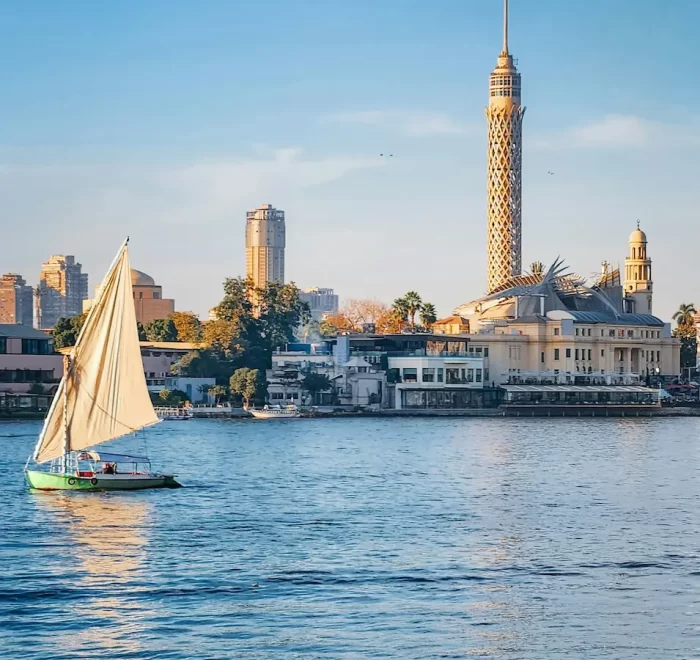 Preguntás Frecuentes Sobre Los viajes a Egipto – Faluca tradicional navegando por el río Nilo en Egipto con cielo azul y orillas con palmeras.