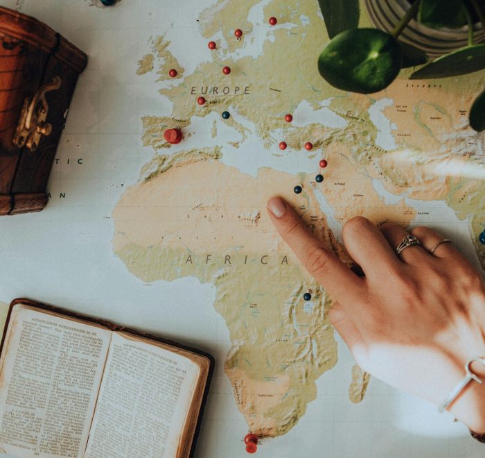 Consejos para Viajar Sola a Egipto: Mujer señalando Egipto en un mapa abierto mostrando rutas y destinos turísticos.