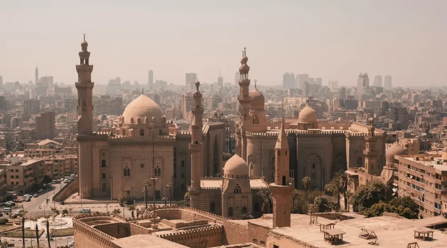 Viajeros frente a monumentos históricos en Egipto incluyendo la Mezquita del Sultán Hassan en Cairo, mostrando la mezcla entre cultura islámica y civilización faraónica